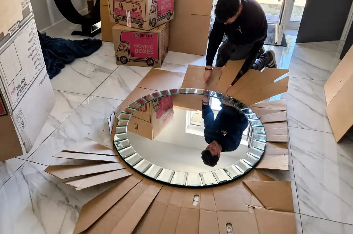 Man packing a large round mirror.