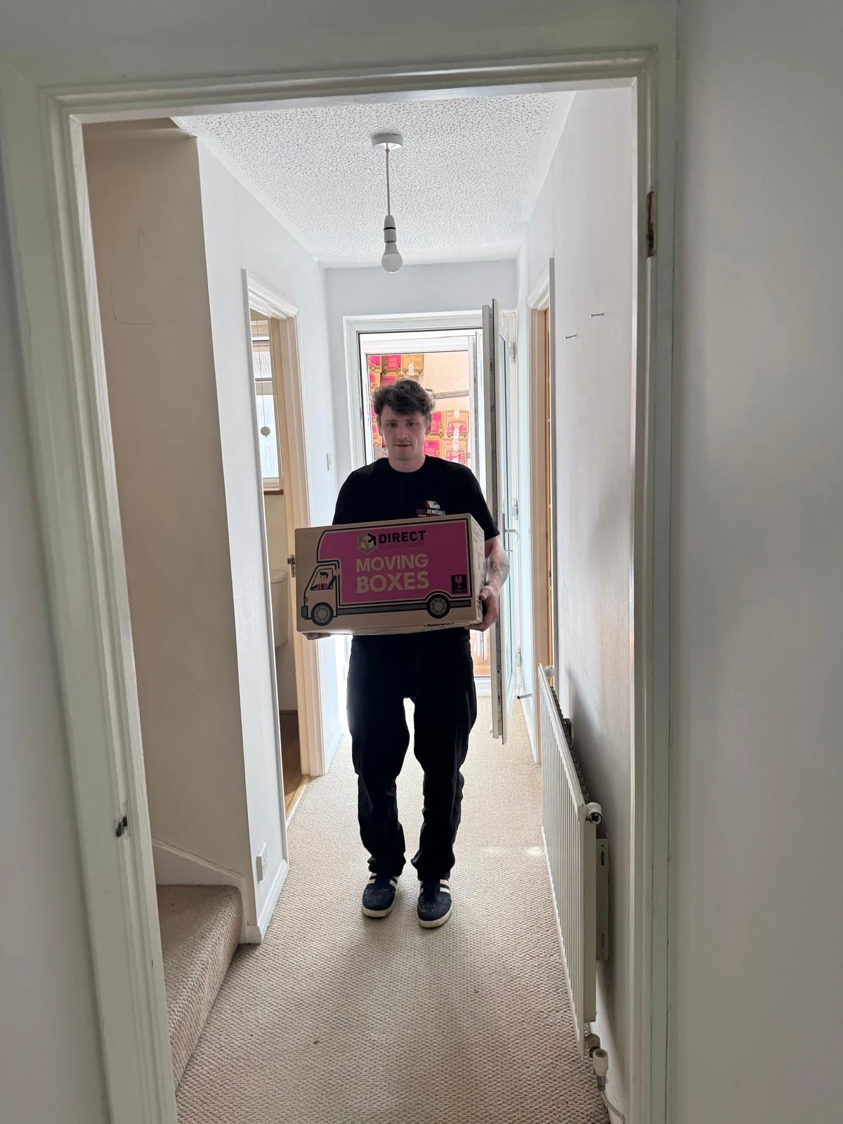 Man carrying a box in the hallway.