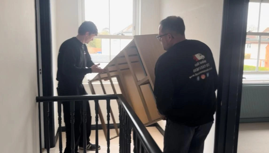 Men moving a cupboard down the stairs.